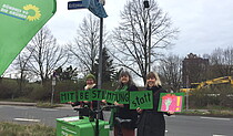 Grüne Frauen stehen unterm Straßenschild Kritzmannstraße/Mechthildstraße und halten Schild - Mitbestimmung.