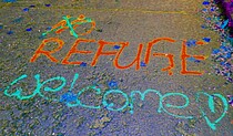 Sprühspruch auf dem Boden "No Refuge" korrigiert zu "Reguge welcome".