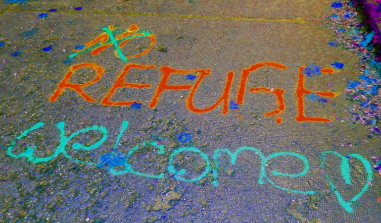 Sprühspruch auf dem Boden "No Refuge" korrigiert zu "Reguge welcome".