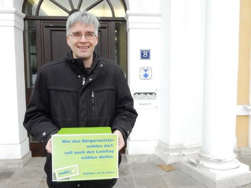 Olaf Meister mit Wahlurne und der Forderung nach Senkung des Wahlalters vor dem Landtag.