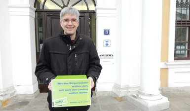 Olaf Meister mit Wahlurne und der Forderung nach Senkung des Wahlalters vor dem Landtag.
