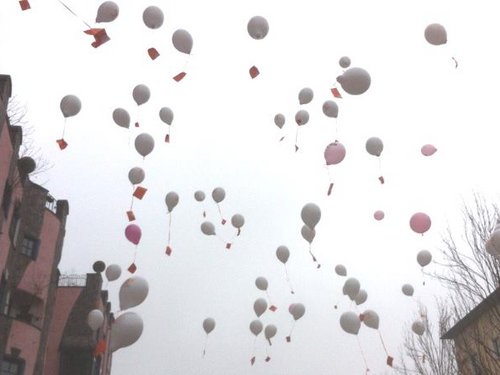 Luftballons steigen am Hundertwasserhaus in den Himmel.